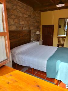 ArgüeroにあるCasa El Prado de la Romiaの白いベッドと石の壁が備わるベッドルーム1室