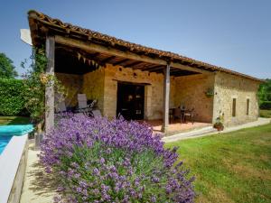 una vista exterior de una casa de piedra con flores púrpuras en Le Nid de Faucons, en Lalinde