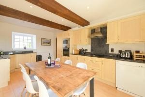 a kitchen with a wooden table and white chairs at The Warren in Bamburgh