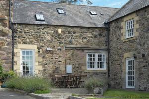 an external view of a stone building with a table and chairs at The Warren in Bamburgh