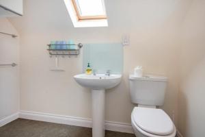a white bathroom with a toilet and a sink at The Old Concert Room in Alnmouth +11 photos
