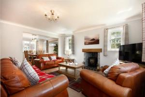 a living room with leather furniture and a fireplace at Castlewood in Bamburgh
