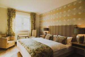 a bedroom with a large bed and a chair at Weingut Hees - Landgasthof Zum Jäger aus Kurpfalz in Auen