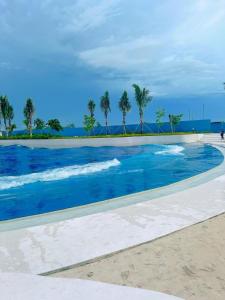 a swimming pool with palm trees in the background at Cozy Studio Unit at Azure North San Fernando Pampanga in San Fernando