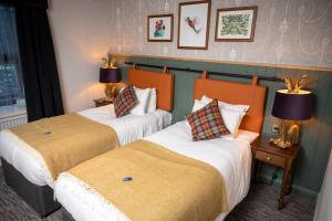 two beds in a hotel room with two lamps at Green Man by Chef & Brewer Collection in Harlow