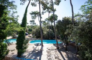 Una piscina con mesa y sillas y árboles. en Huttopia Oleron Les Pins, en Saint-Trojan-les-Bains 25 fotos más