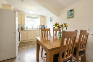 een keuken met een houten tafel en een koelkast bij Middlemoor Cottage in Alnwick