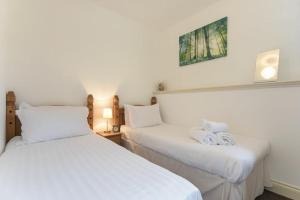 two beds in a room with white sheets and towels at Middlemoor Cottage in Alnwick