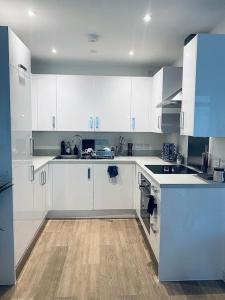 a kitchen with white cabinets and a wooden floor at Stunning 1 Bed Luxury Apartment in Erith