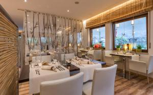 un restaurante con mesas y sillas blancas y ventanas en Hotel Bamboo, en Coldrano