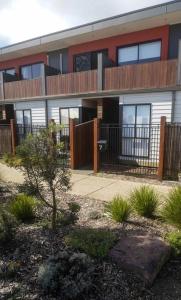 a building with a fence and a tree in front of it at Modern air-conditioned 3-bedroom townhouse in centre of Cape Woolamai in Cape Woolamai