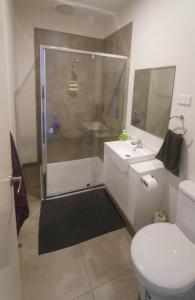 a bathroom with a shower and a toilet and a sink at Modern air-conditioned 3-bedroom townhouse in centre of Cape Woolamai in Cape Woolamai