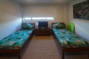 Cette chambre comprend deux lits et un bureau avec une télévision. dans l'établissement Modern air-conditioned 3-bedroom townhouse in centre of Cape Woolamai, à Cape Woolamai