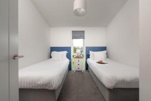 two beds in a room with white and blue at Bluebell Lodge, 29 Roadford Lake Lodges in Lifton