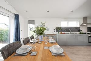a dining room with a table and chairs and a kitchen at Bluebell Lodge, 29 Roadford Lake Lodges in Lifton
