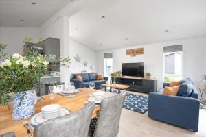 a living room with a table and blue furniture at Bluebell Lodge, 29 Roadford Lake Lodges in Lifton