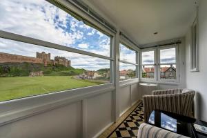 a room with a window with a view of a castle at Keeper's View in Bamburgh