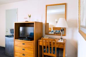 a bedroom with a tv and a dresser with a mirror at Budget Host Alexandria in Alexandria