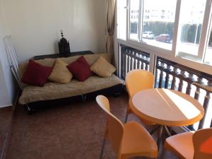 Marina Apartment Agadir في أغادير: غرفة معيشة مع أريكة وطاولة وكراسي