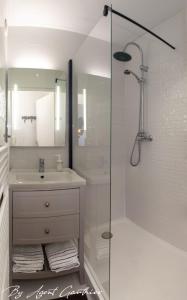 La salle de bains blanche est pourvue d'un lavabo et d'une douche. dans l'établissement Charmant 2 pièces les pieds dans l'eau, à Sète
