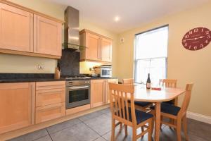 a kitchen with a table and a clock on the wall at Churchside in Alnwick