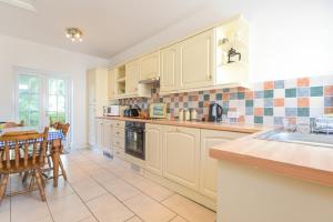 a kitchen with white cabinets and a table and a sink at Dunlin Cottage in Bamburgh +9 photos