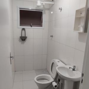 a white bathroom with a toilet and a sink at Cristal da Vista Linda Apartamento 03 in Bertioga