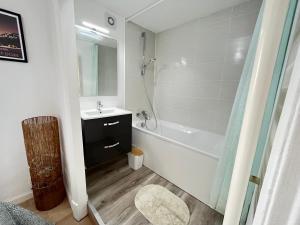 La salle de bains est pourvue d'une baignoire blanche, d'un lavabo et d'une baignoire. dans l'établissement Le Cliersou - Appartement bien situé à Clermont-Ferrand Fontgieve, à Clermont-Ferrand