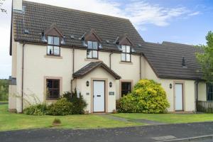una casa blanca con techo negro en Smithy Court, en Craster