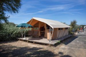 a tent with a table and an umbrella at Huttopia Côte Sauvage - Ile de Ré in Sainte-Marie-de-Ré