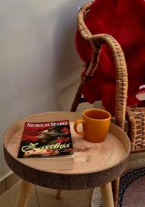 ein Buch und eine Tasse auf einem Tisch mit einem Stuhl in der Unterkunft Duplex Rooms in Korçë