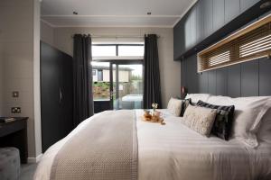una gran cama blanca con un osito de peluche sentado en ella en Hawthorne Lodge, 15 Roadford Lake Lodges, Lifton, en Lifton