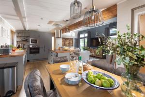 cocina y sala de estar con mesa y un bol de fruta en Hawthorne Lodge, 15 Roadford Lake Lodges, Lifton, en Lifton