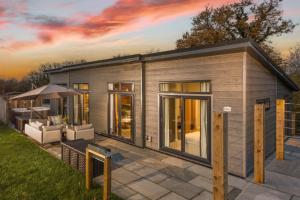 a tiny house with a patio and an umbrella at Hawthorne Lodge, 15 Roadford Lake Lodges, Lifton in Lifton