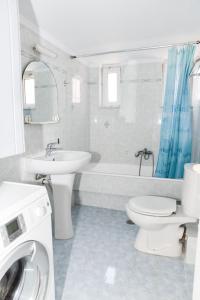 La salle de bains blanche est pourvue d'un lavabo et de toilettes. dans l'établissement Aposperite Apartment, à Kalamata