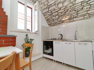 a kitchen with white cabinets and a brick wall at Studio Joković in Vela Luka