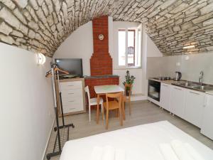 a kitchen with a table and a brick fireplace at Studio Joković in Vela Luka