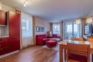 cocina y sala de estar con sofá rojo y mesa en Hafendomicil Appartement WH06 - Hase, en Waren
