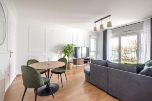 ein Wohnzimmer mit einem Sofa, einem Tisch und Stühlen in der Unterkunft La Parisienne by Plaza in Montévrain