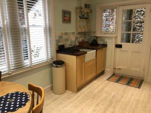 a kitchen with a sink and a table and a door at Seaview Cottage in Broadstairs