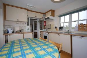 a kitchen with white cabinets and a blue and yellow checkered table at Snook Point Cottage in Newton-by-the-Sea