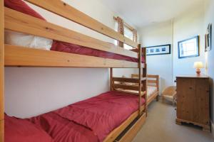 a bedroom with two bunk beds with red sheets at St Marys Cottages No4 in Embleton