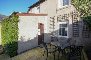 a patio with a table and chairs in front of a building at St Marys Cottages No4 in Embleton