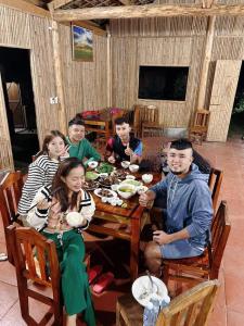 a group of people sitting around a wooden table at Bình Minh Homestay in Nam Giang