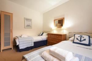 a bedroom with two beds and a dresser with a mirror at Spinnaker in Embleton