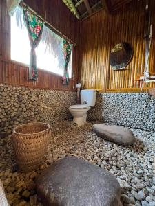 a bathroom with a toilet and a rock floor at Bình Minh Homestay in Nam Giang