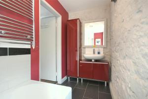 a bathroom with a sink and a red wall at Stonecrop Cottage in Alwinton