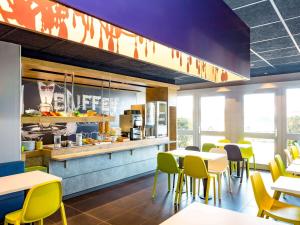 a dining room with tables and yellow chairs at ibis budget Quimper in Quimper