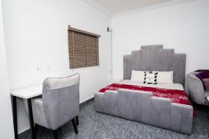 1 dormitorio con cama, escritorio y silla en Ebrina Apartments en Port Harcourt