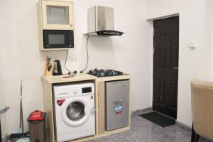 a kitchen with a washing machine and a microwave at Ebrina Apartments in Port Harcourt